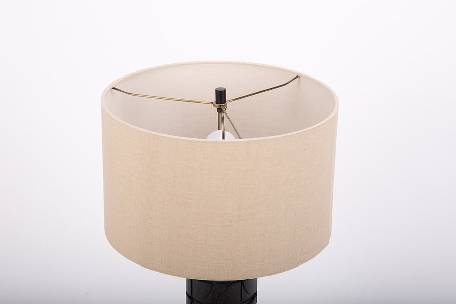 Mimi lamp with a beige linen shade and mate-black body with dimensional carving pattern. Closed up view on the body.