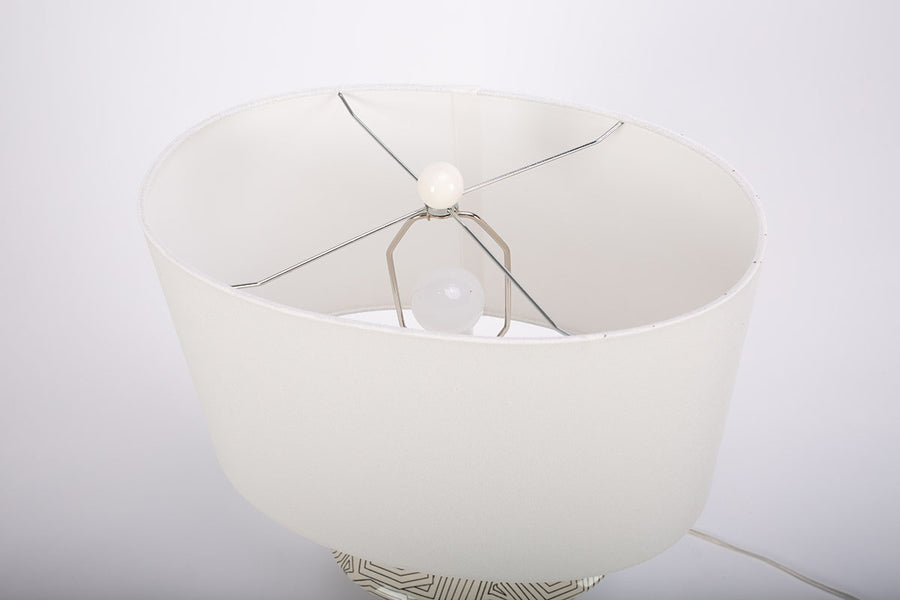Toronto table lamp with white drum shade and geometric black design that contrasts the ivory ceramic gloss creating an unusually artful combination. Closed up top view on the shade.