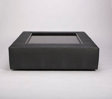 Black Zai Ottoman with padded top perimeter and wood applications on the top surface.