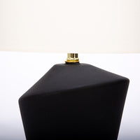 Gavin table lamp with a drum white shade and modern black ceramic body in an unique asymmetric design and a contrasting gold base. Closed up partial view of the body and the shade.