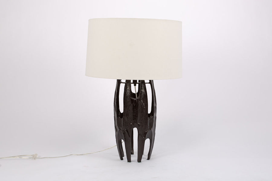 Naomi Lamp with an off-white linen drum shade and the black body done in the Brutalist style characterized by abstracted organic forms with rough textures.