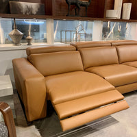 Orange leather Vogue three seater sofa equipped with a state of the art power mechanism and touchpad that individually controls headrest and footrest. Left side reclined.