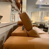 Orange leather Vogue three seater sofa equipped with a state of the art power mechanism and touchpad that individually controls headrest and footrest. Closed up side view.